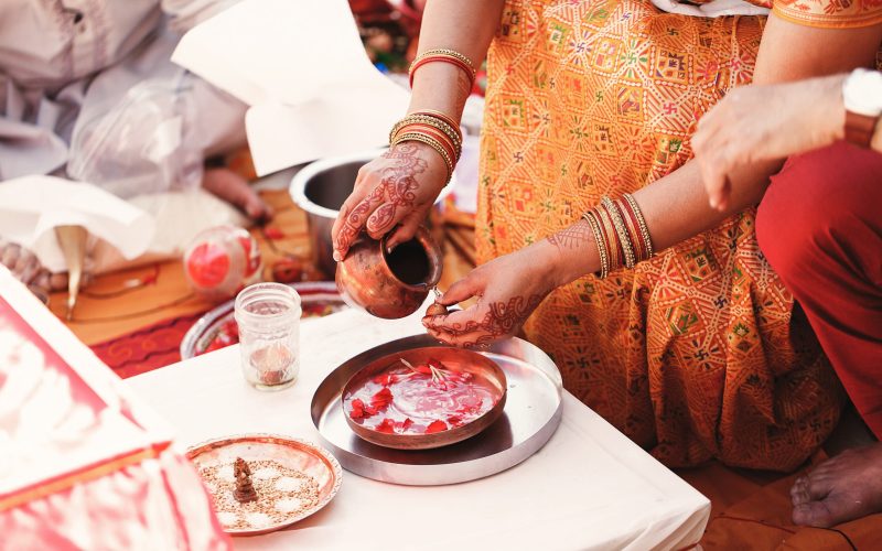 Indian bride washes nuts over the plate with species and petals